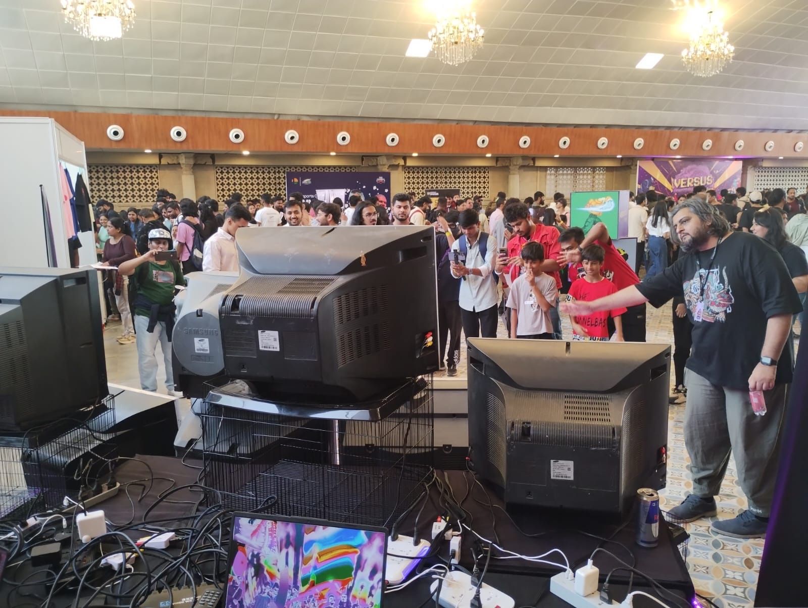 Visitors gather beyond the CRT stack and live camera system at Versus Festival.