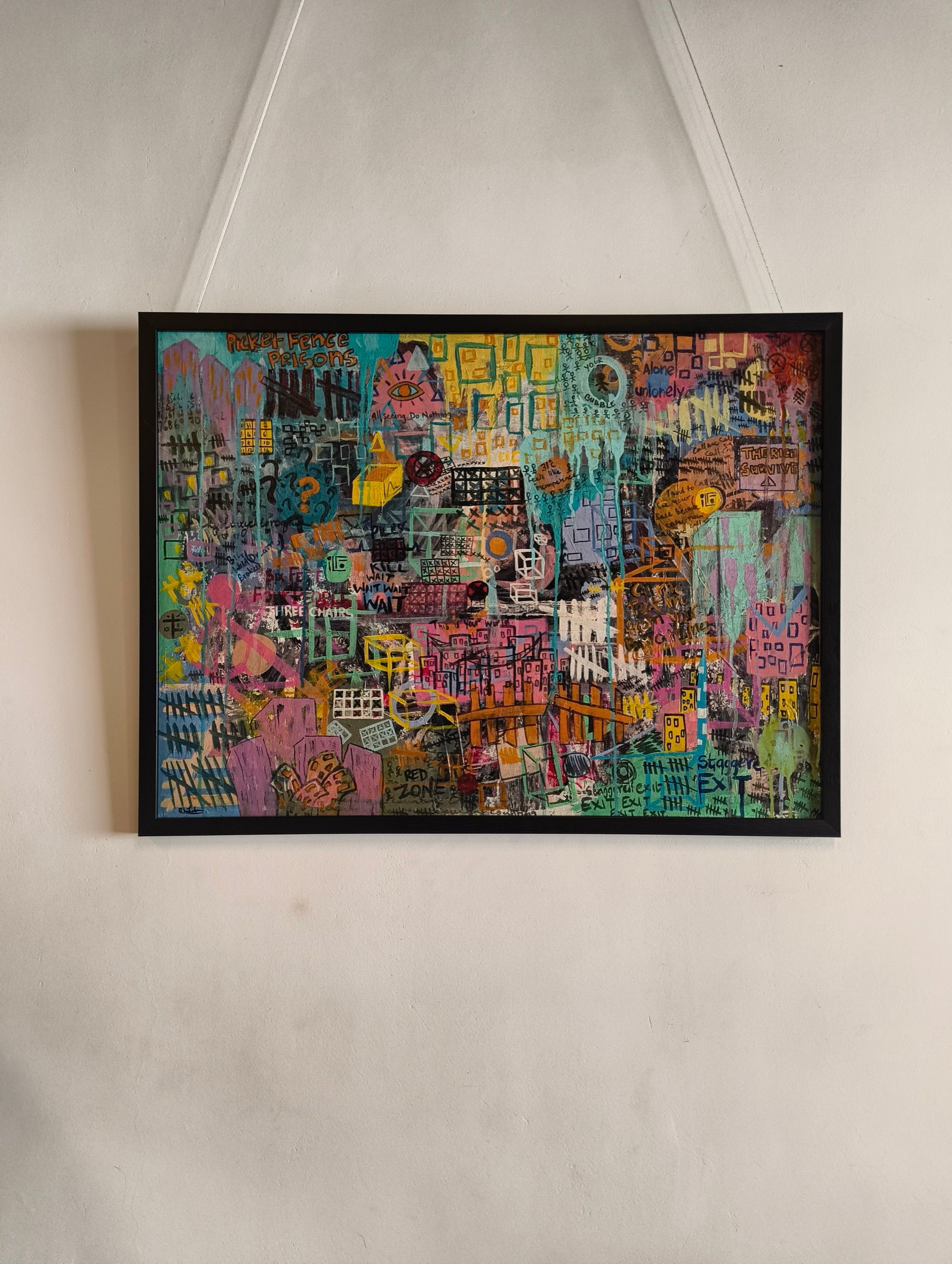 A colourful layered cityscape painting displayed in a black frame at the exhibition.