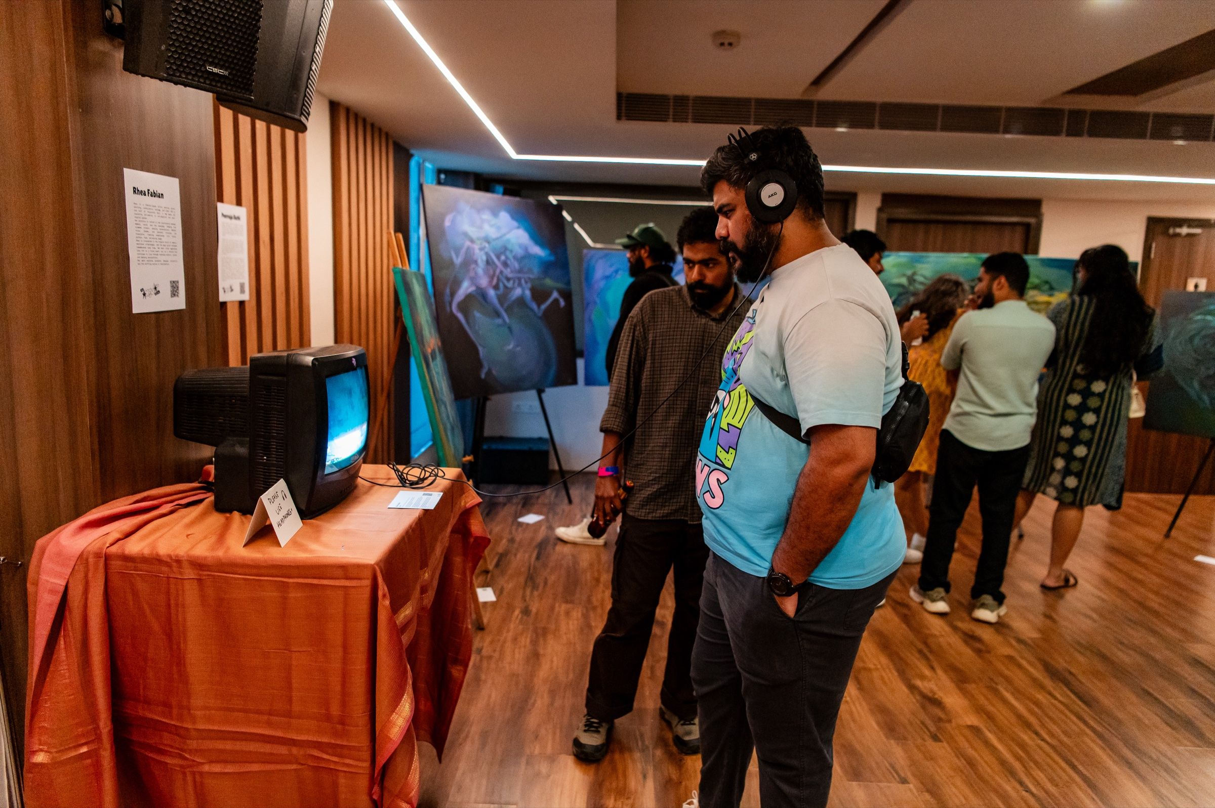 A visitor listens through headphones while watching Glitter on a CRT television.