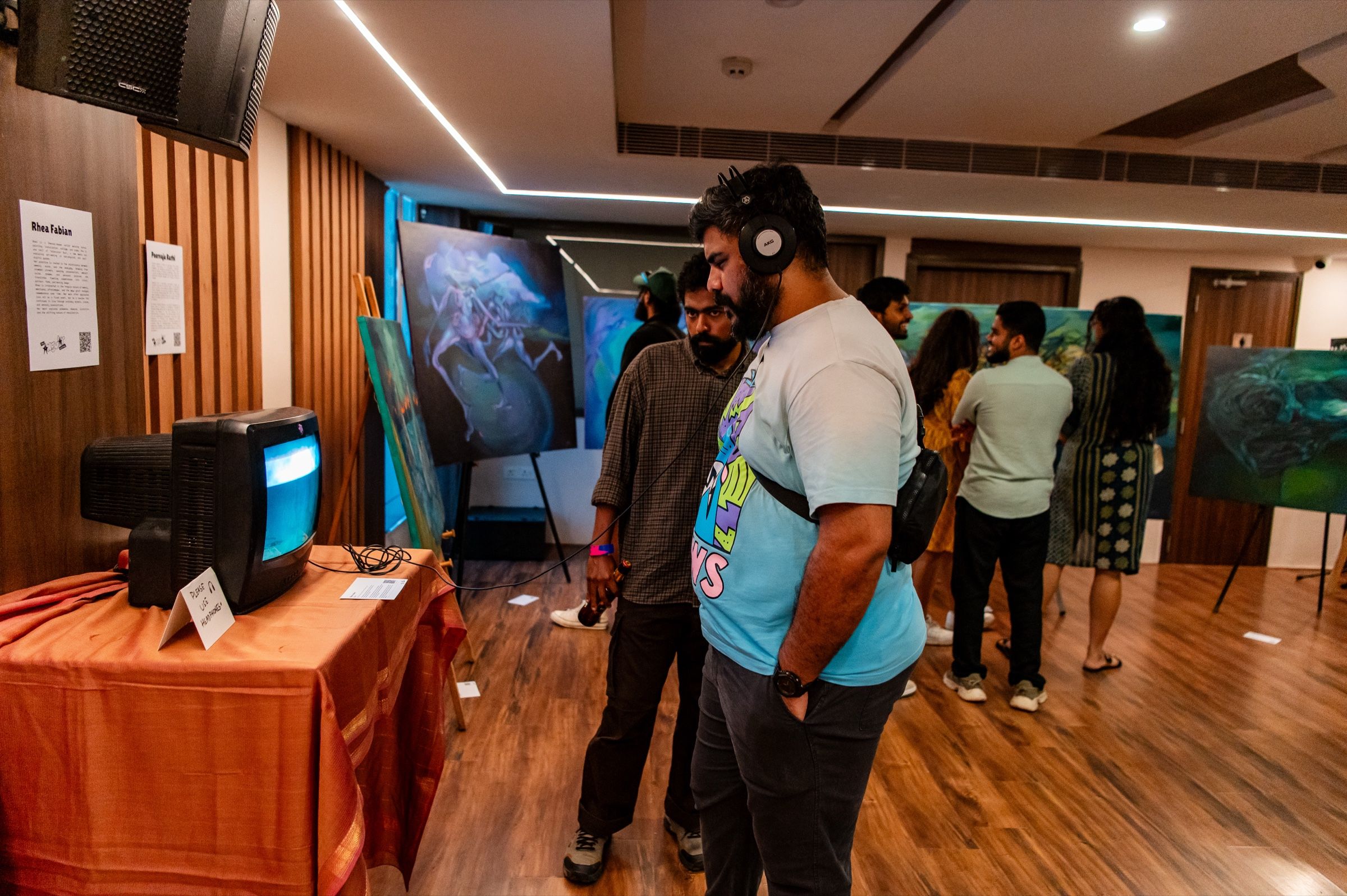 A visitor listens on headphones while watching Glitter on a CRT television in the festival gallery.