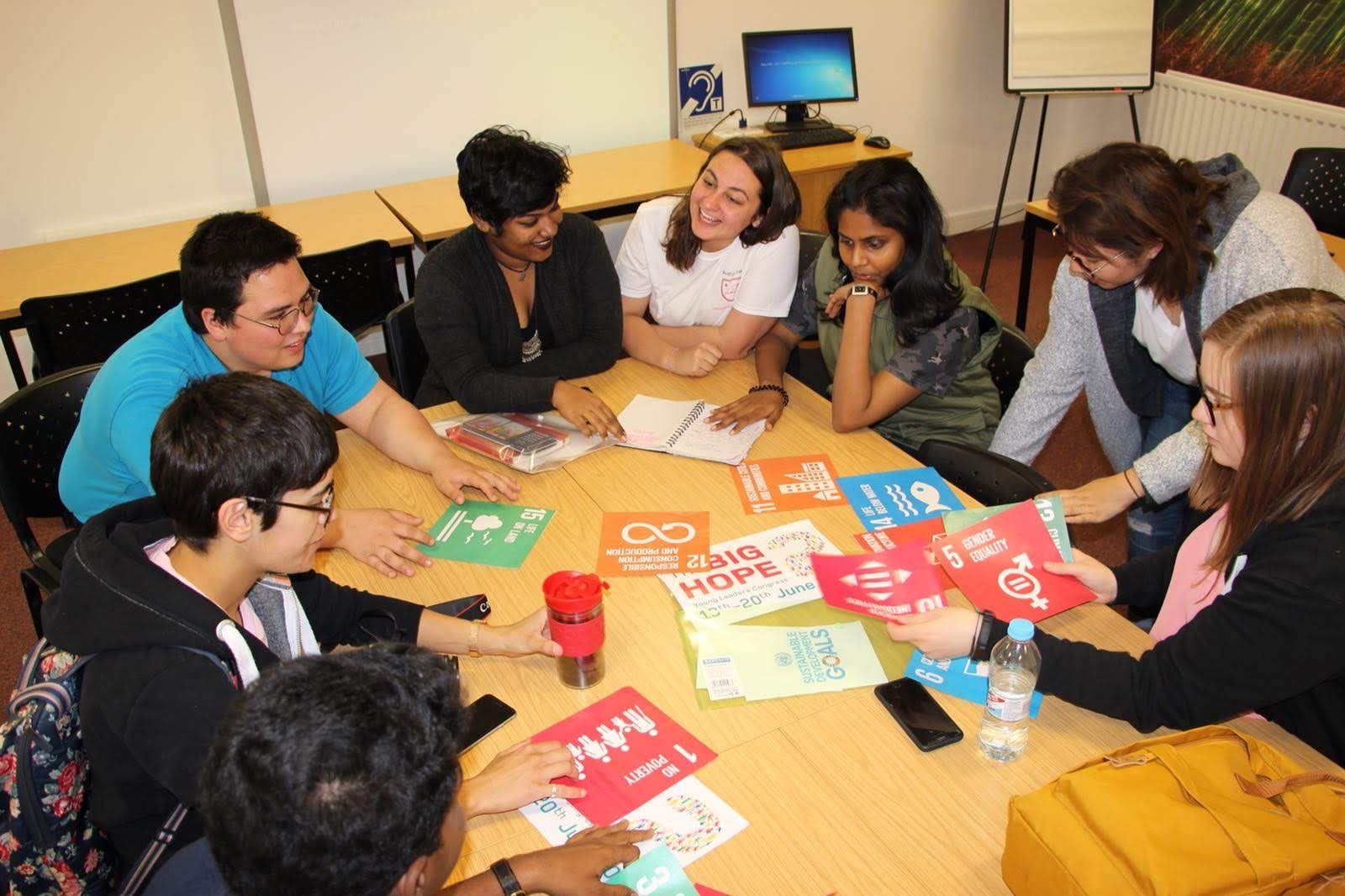 International delegates discussing the Sustainable Development Goals around a workshop table.